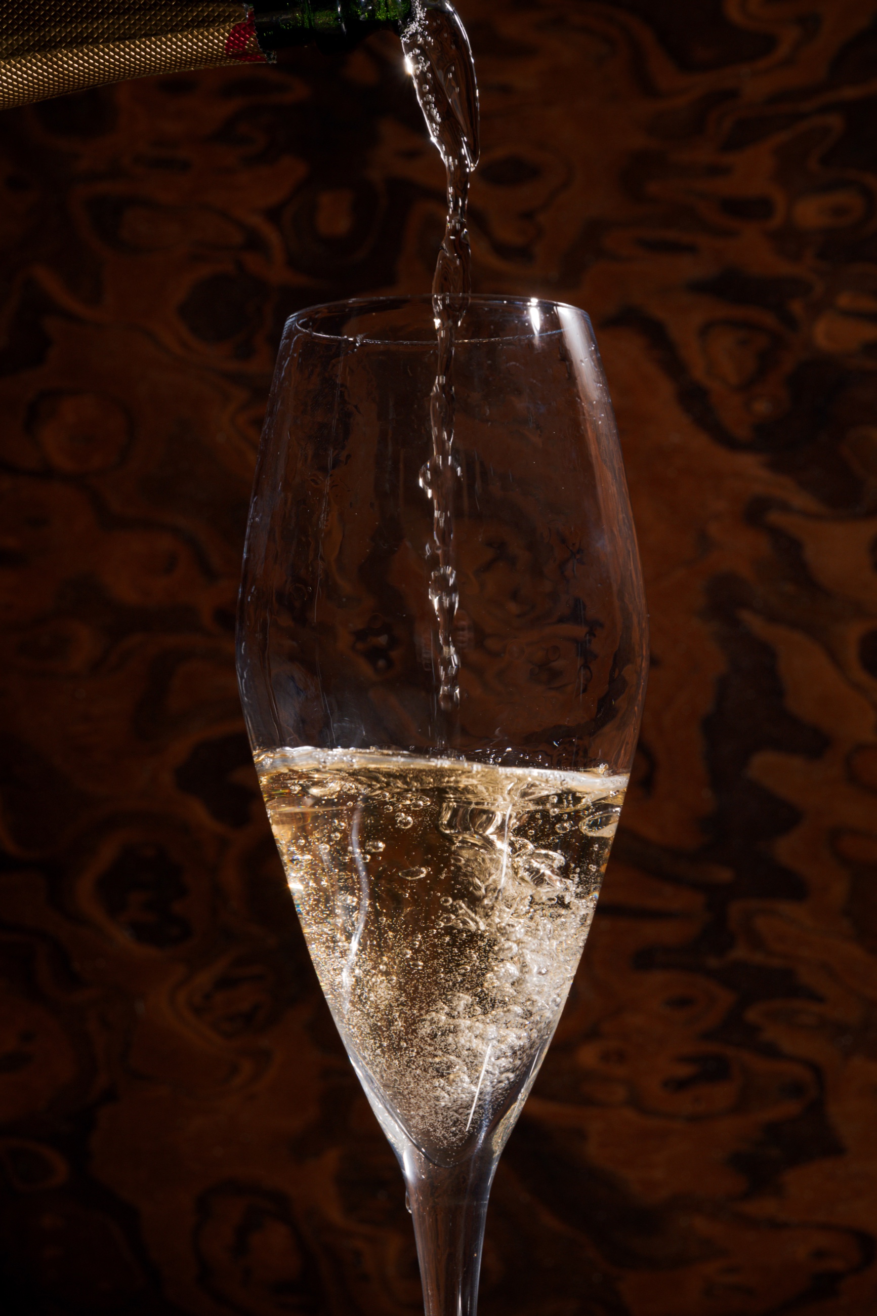 Champagne being poured into flute against marble wall