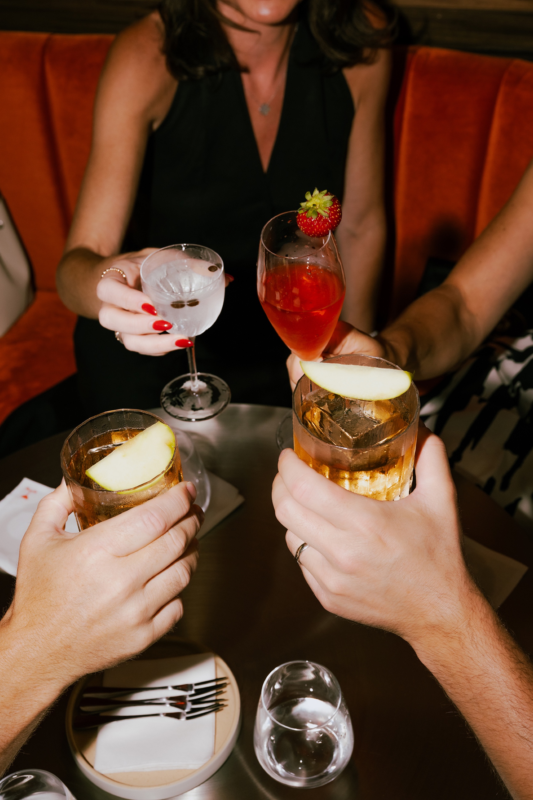 Friends cheersing four cocktails
