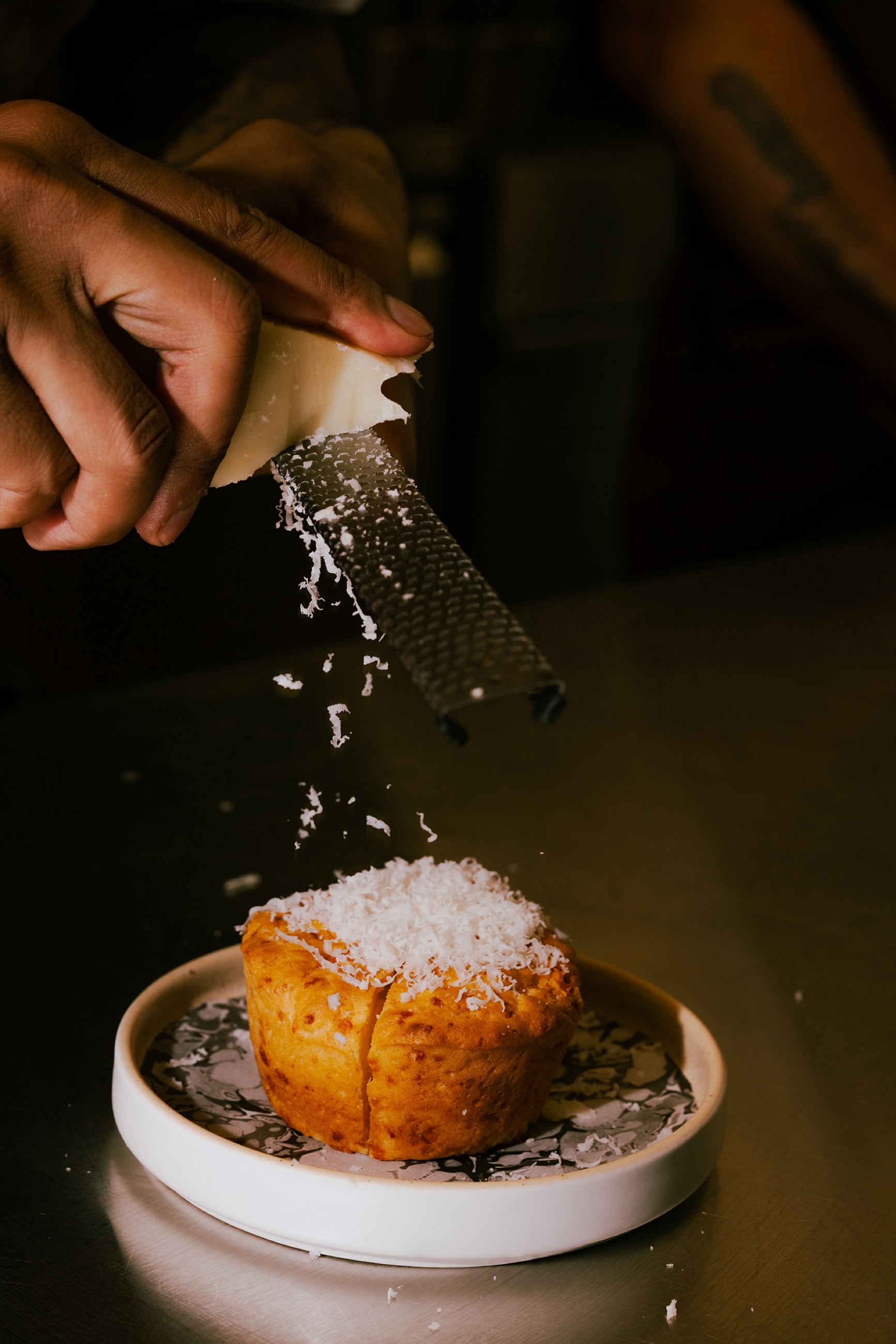 Cheese being grated over a plated pastry