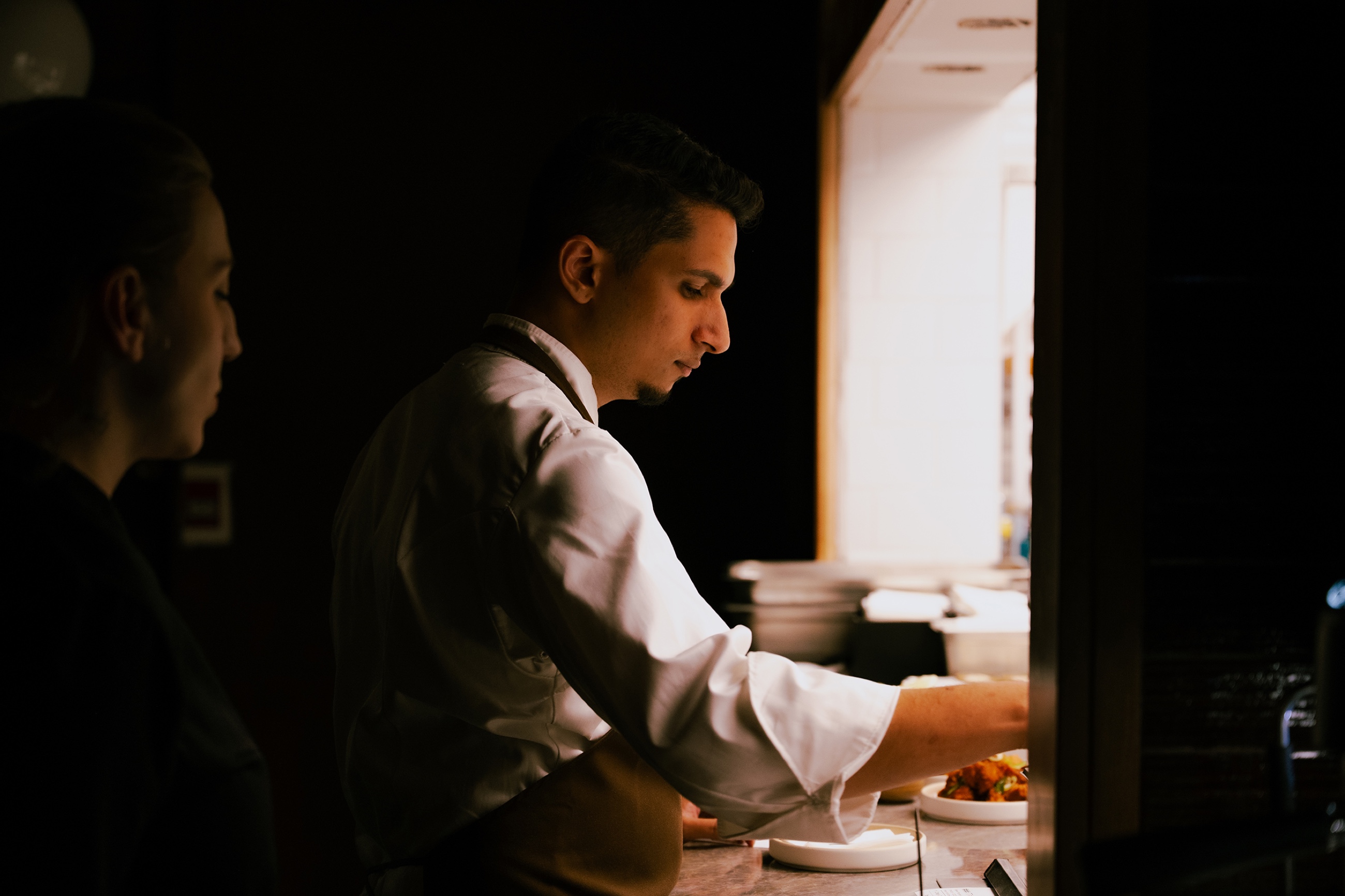 Chef at the pass in dramatic side light