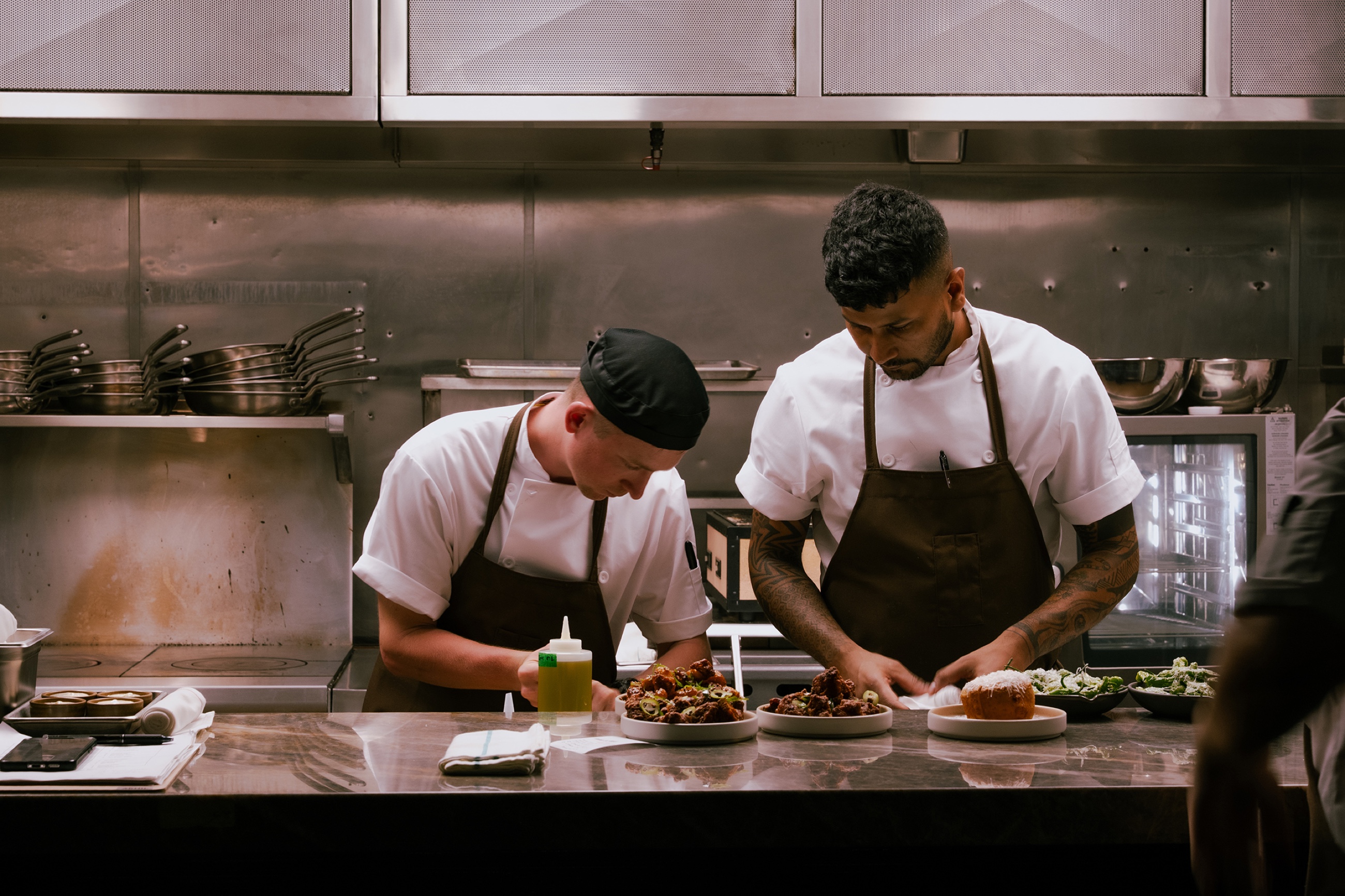 Two chefs plating dishes at the pass