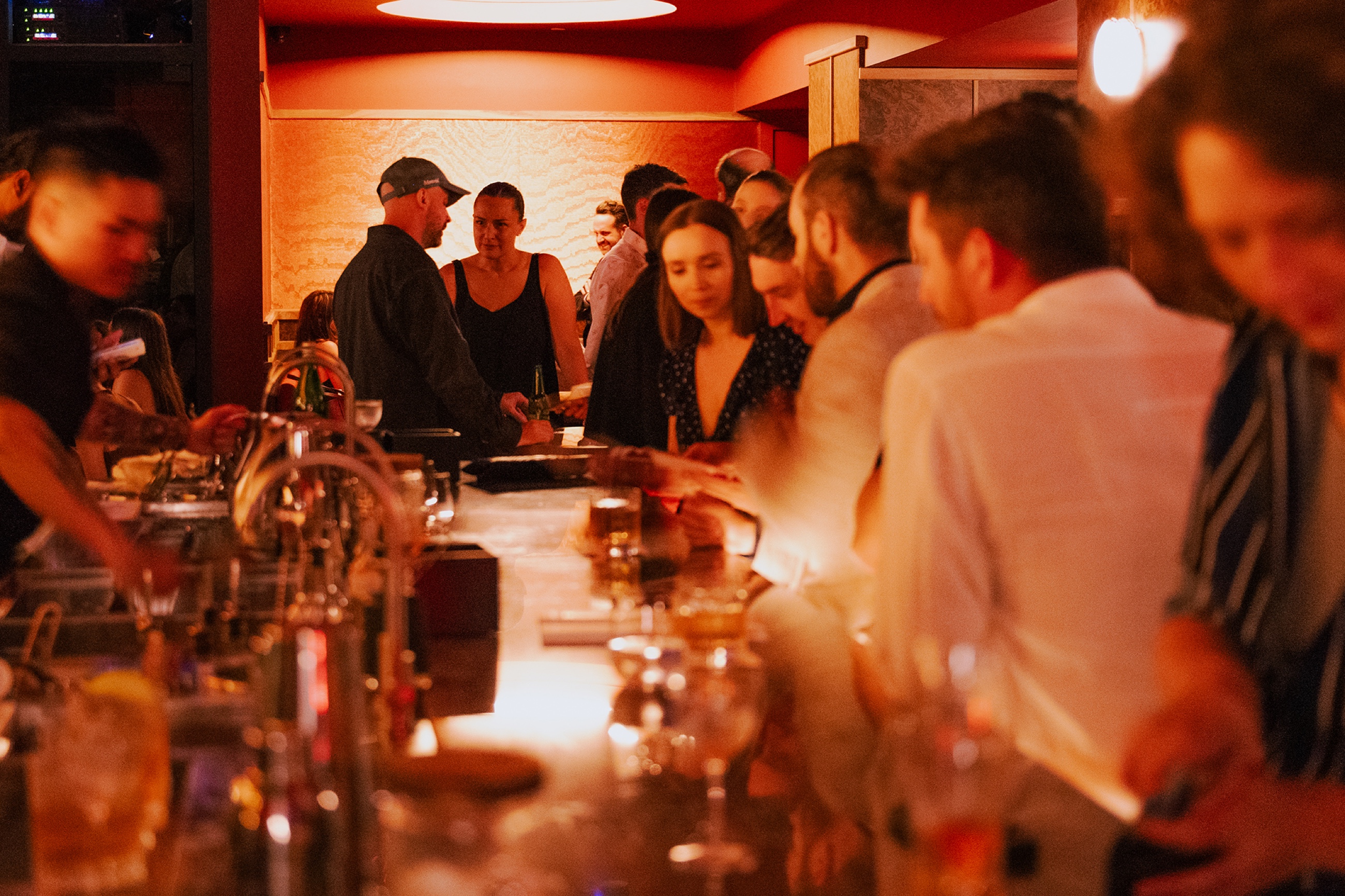 Crowded bar counter, guests and warm lighting