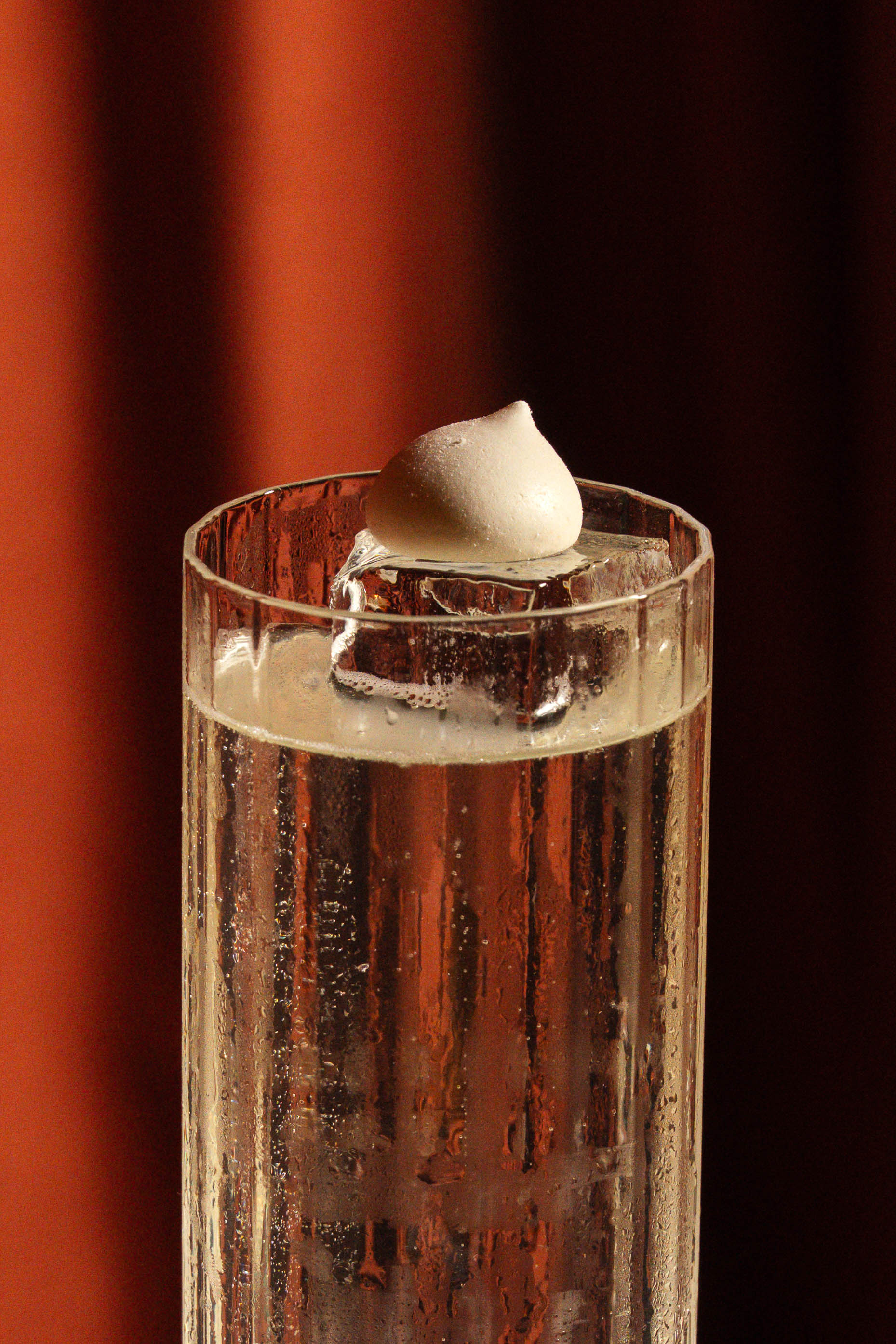 Tall Manhattan-style highball with a pale garnish on clear ice