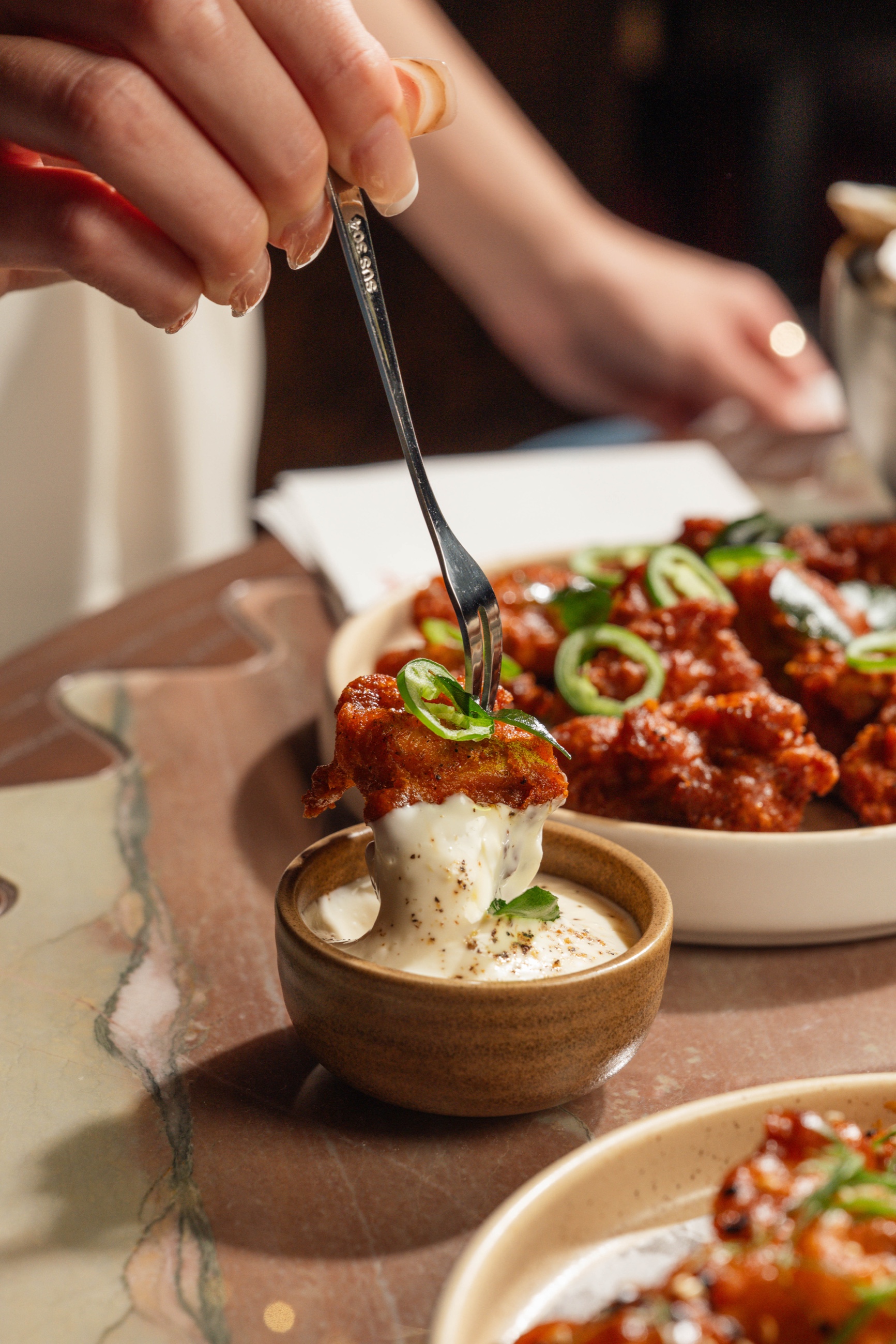 Guest lifting a fried bite from a bowl with dipping sauce