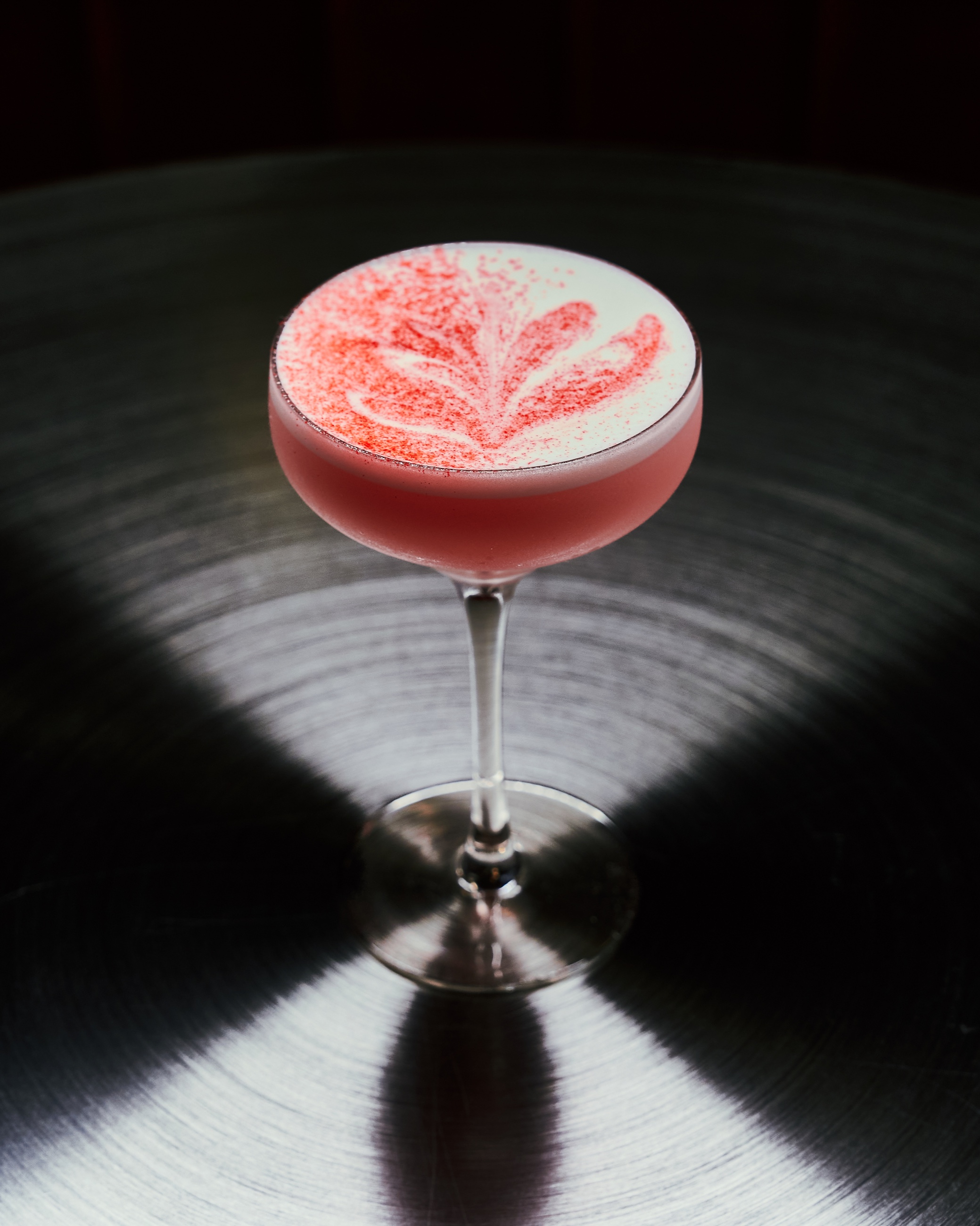 Pink coupe on black table with red velvet banquette