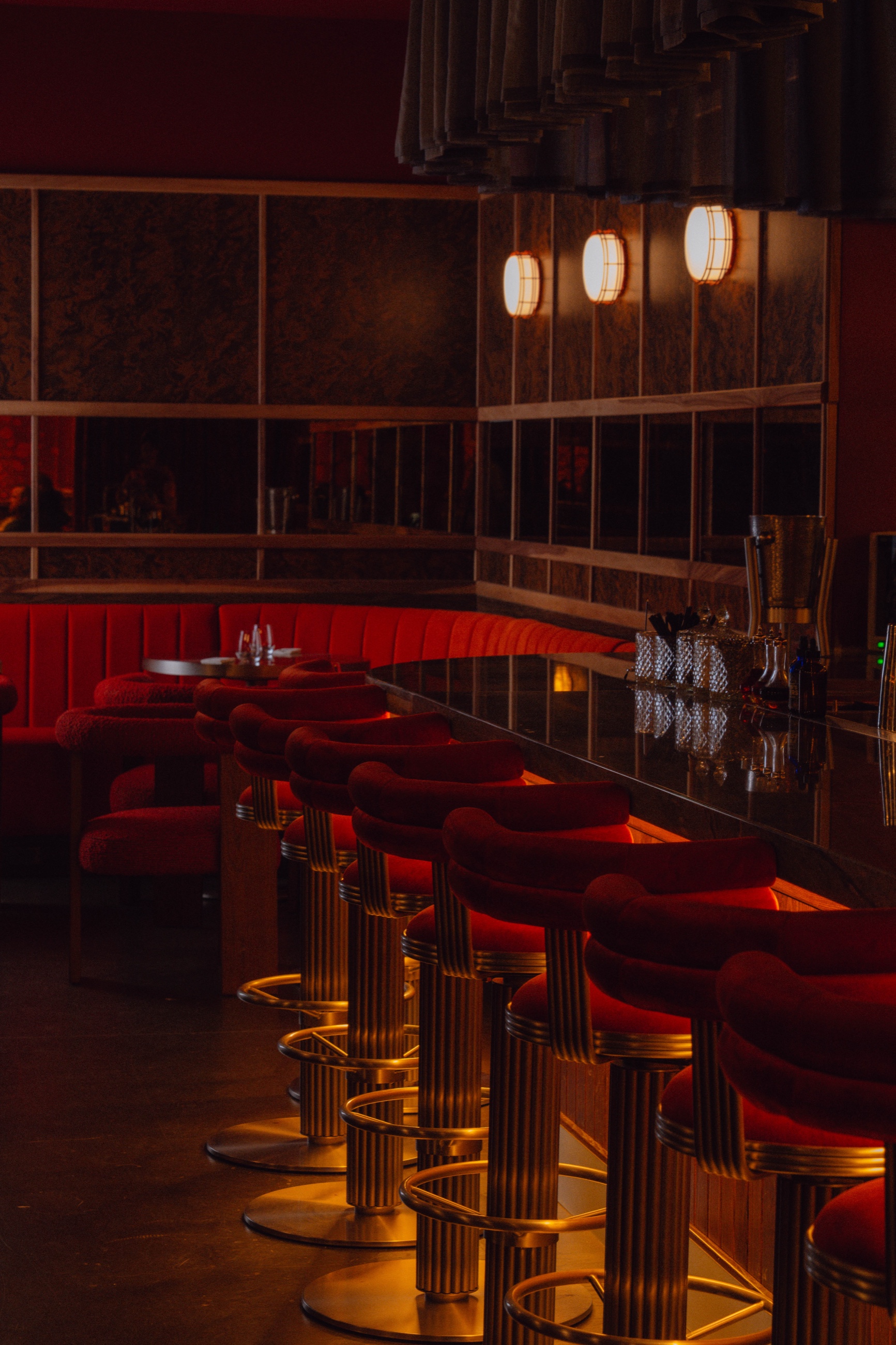 Long bar corner with red stools and glowing sconces